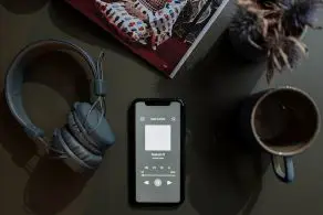 Headphones, a cellphone, and a coffee cup on a table