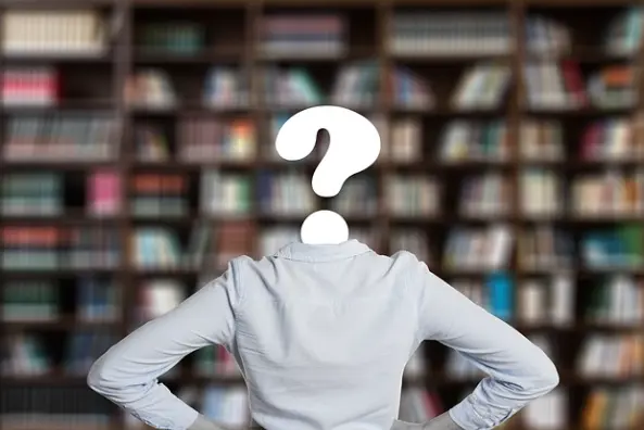 A student facing a wall of library books with a question mark instead of a head to indicate confusion