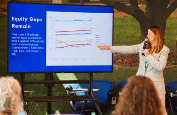 Presenter pointing to a digital slide that reads